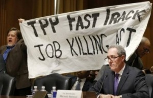 TPP-Protest-Froman-miffed-as-KZ-and-Dick-Ochs-hold-banner-behind-him.-Source-Reuters.-e1429808714476